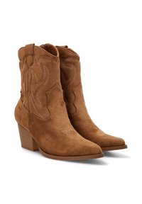 Botas de vaquero de ante marrón hasta el tobillo, con puntas afiladas, tacones apilados y costuras decorativas a lo largo de los lados.