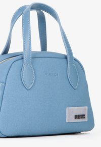 Borsa a mano azzurro chiaro realizzata in materiale testurizzato, dotata di chiusura con zip, due manici superiori e una toppa rettangolare con logo.