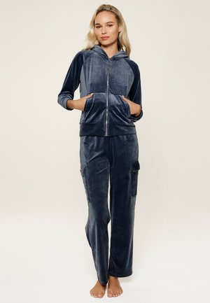 Navyblauw fluwelen loungewear set met een ritskap met zakken en cargobroek. Zachte textuur met een comfortabele pasvorm.