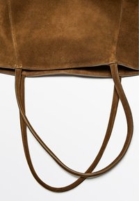 Bruine suède tote bag met platte handvatten, een eenvoudig ontwerp en zichtbare stiksels langs de randen voor versteviging.