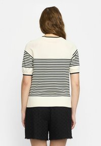 Beiger Kurzarmpullover mit schwarzen horizontalen Streifen, Rundhalsauschnitt, gerippten Bündchen und einem Saum, der auf der Taille sitzt.
