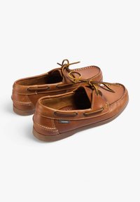 Bruine leren bootschoenen met een gladde textuur, rubberen zool en contrasterende gele veters. Kenmerkt gestikte details en branding aan de zijkant.