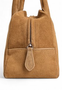 Ruskea mokkanahasta valmistettu käsilaukku, jossa on vetoketjukiinnitys, teksturoitu pinta ja pieni etutasku. Mukana sileät nahkakoristeet ja matching-ompeleet.