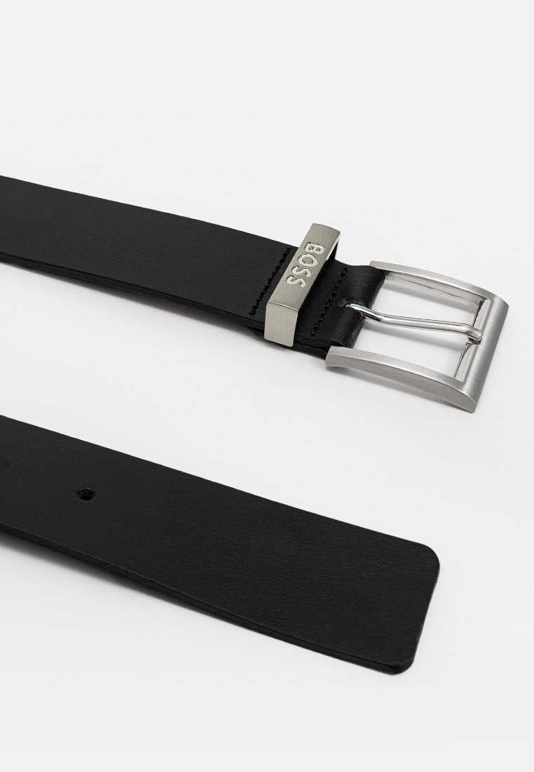 Zwarte leren riem met een zilveren metalen gesp met merkgravure. Glad oppervlak, rechthoekige vorm en meerdere verstelgaten.