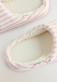 Striped indoor slippers with a soft white fabric and pink stripes. The interior is textured, featuring a quilted pattern. Brand label visible.