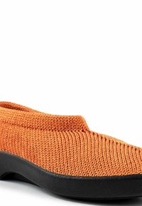 Scarpa slip-on arancione lavorata a maglia con tomaia testurizzata, suola in gomma nera e design a profilo basso. Presenta una punta arrotondata e colletto elastico.