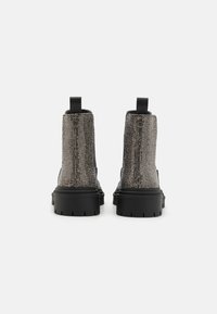 Bottes à plateforme noires avec une tige en tissu gris texturé, dotées de deux poignées, bout rond et semelle en caoutchouc avec des rainures.