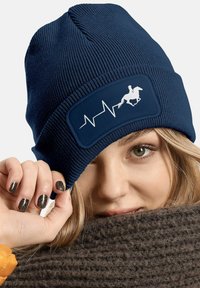 Navy knitted beanie with ribbed texture, featuring a rectangular patch with a white horse silhouette and heartbeat line design.