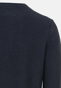 Pull en maille bleu marine avec une finition texturée, un col rond et une coupe ajustée. Le dos présente un détail de couture discret.