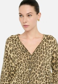Cardigan de estampado de leopardo en color marrón claro y marrón oscuro, diseño de cuello en V, con botones de acentos metálicos y una textura suave.