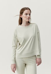 Ljusgrön, långärmad sweatshirt tillverkad av ett glatt tyg med en avslappnad passform och något droppade axlar, med en ribbad halsringning.