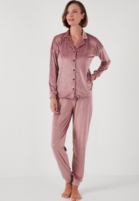 Satin set za pidžamu u mekoj ružičastoj boji, s dugim rukavima, gumbima sprijeda i elastičnom pojasom. Glatka tekstura s opuštenim krojem.