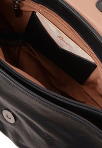 Zwarte leren tas open met bruine stoffen binnenkant, ritsvak en kaartvak met een beige kaartje waarop "Merci" staat.