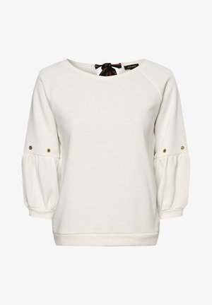 Valkoinen pitkähihaisen puseron puffihihoilla, joissa on kultaiset napit ja musta-ruskearaidallinen solmuke takakaula-aukon kohdalla.