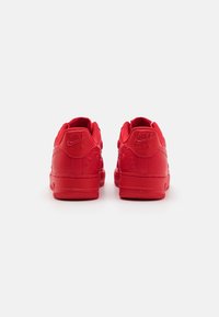 Crvene Nike Air cipele izrađene od glatke kože, niskog dizajna, s reljefnim cvjetnim detaljima i teksturiranim gumama.
