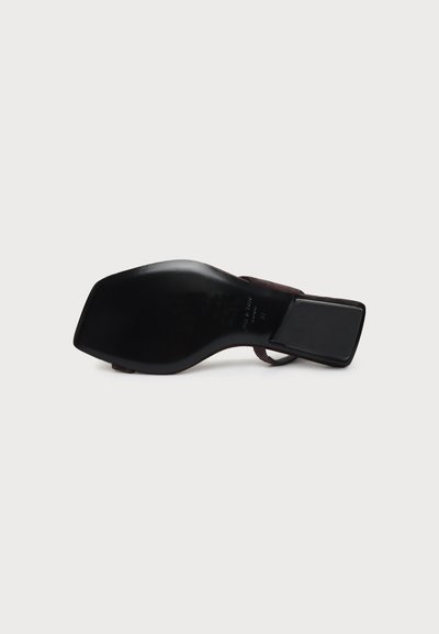 Sandale à talon pour femme avec semelle noire, bout carré et talon bloc bas, vue par le dessous sur fond blanc.