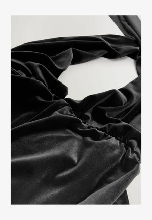 Schwarzer Samtstoff mit weicher Textur, gerafftem Design, drapierenden Falten und glatter Oberfläche, der Eleganz in der Einfachheit vermittelt.