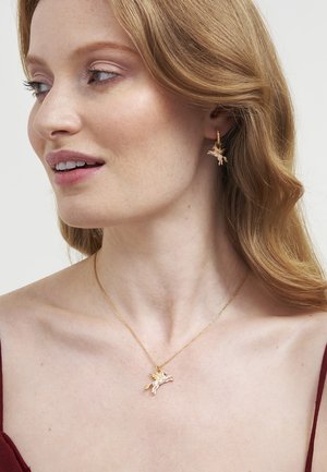 Nakit v zlatem tonu, ki vključuje ogrlico z detajlno obeskom enoroga in ujemajoče se uhane, ki imajo gladko površino in nežno verižico.