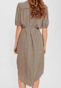 Abito midi a stampa floreale in morbido tessuto, con maniche a palloncino corte, vita cinchata e orlo curvo. Predominantemente beige con macchie multicolori.