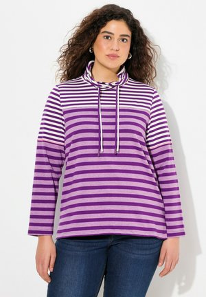 Maglietta a maniche lunghe a righe viola con collo a cowl e coulisse. Il materiale è morbido e presenta ampie righe orizzontali in diverse tonalità di viola.