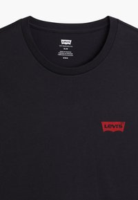 Svart bomull t-skjorte med slim fit, rund hals og en liten rød Levi's-logo nær venstre brystområde.