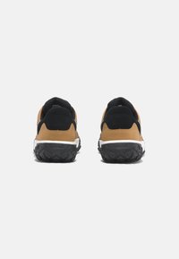 Zapatillas deportivas con una parte superior en tonos marrón claro y detalles en negro, suela de goma texturizada y talón acolchado para mayor soporte.