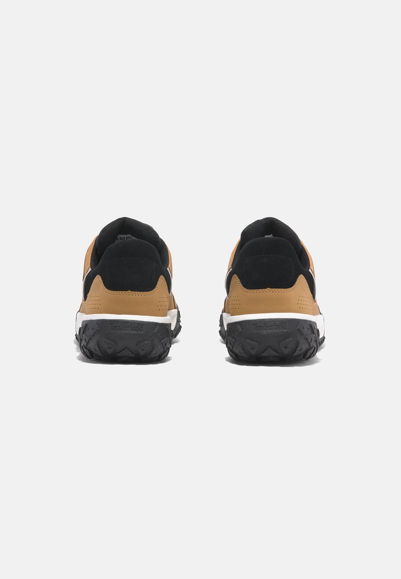 Sportieve schoenen met een tan bovenwerk en zwarte accenten, een gestructureerde rubberen buitenzool en een gevoerde hak voor extra ondersteuning.