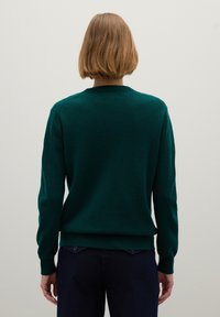 Suéter verde oscuro hecho de una tela suave, con mangas largas, escote redondo y puños y dobladillo acanalados. Costura visible en la parte trasera.