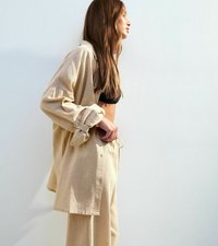 Beige, linne knäppt skjorta i oversized modell med upprullade ärmar, matchad med svart bralette och matching byxor med dragsko. Slät textur, avslappnad passform.
