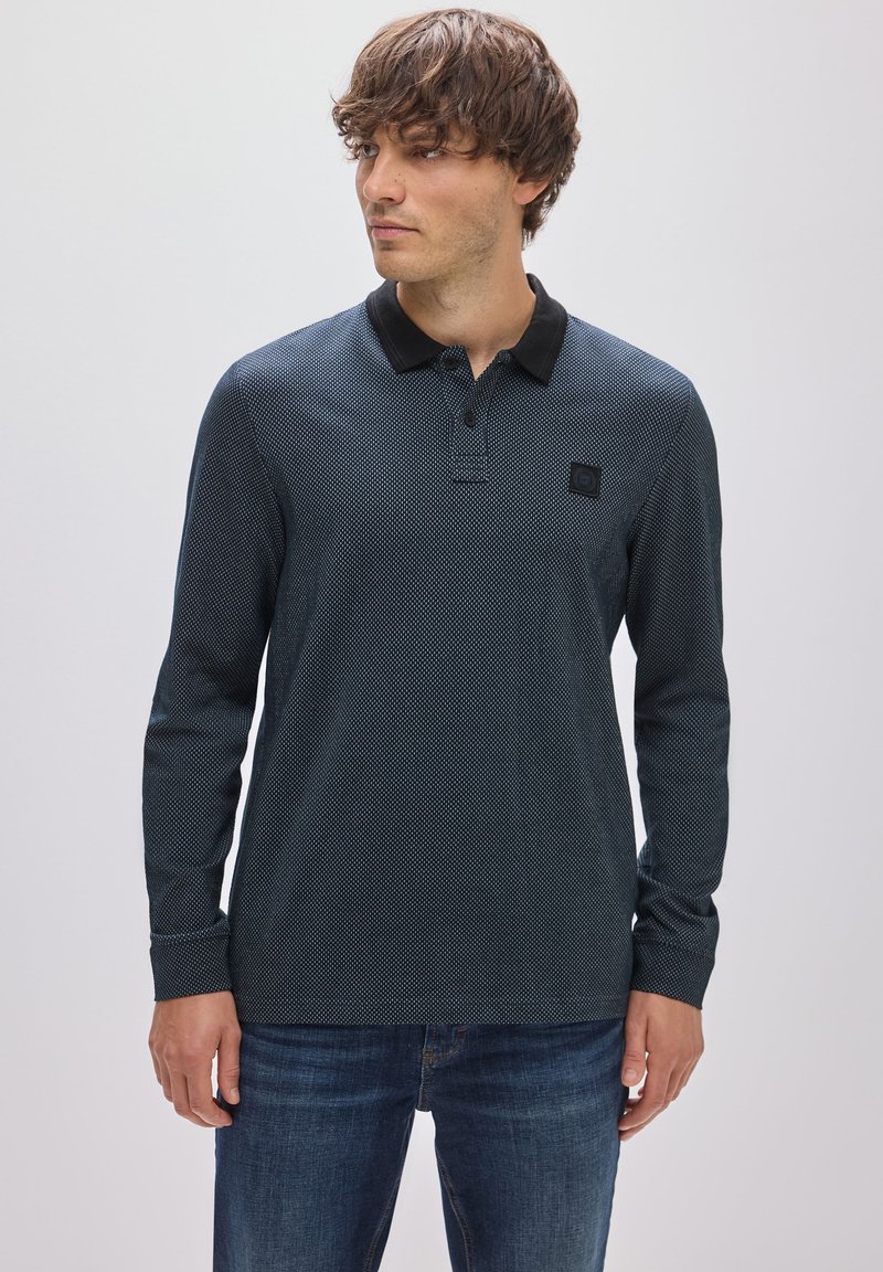 Langärmliges Polohemd in Dunkelblau mit strukturiertem Muster, schwarzem Kragen, einer drei-knopfigen Knopfleiste und einem kleinen Logo-Patch auf der Brust.