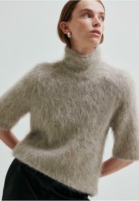 Ljusgrå, kortärmad tröja med hög hals, tillverkad av fluffigt, texturerat material, som har en löst sittande passform och mjuk utseende.