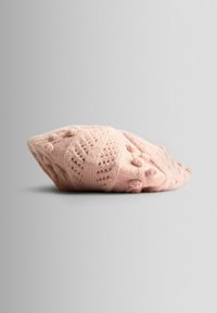 Dzianinowy beret w miękkim różu, z wystającymi wzorami i detali w postaci pomponów, o okrągłym kształcie i teksturowanym wykończeniu.