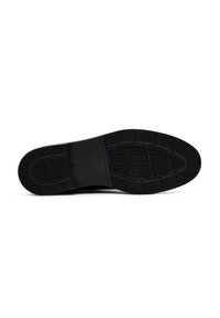 Suola di scarpa nera in gomma testurizzata con grip a motivo, punta tonda e sezione centrale rialzata. Completamente piatta senza accentuazioni visibili.