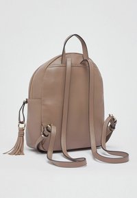 Sac à dos en cuir marron à forme arrondie, fermeture éclair, bretelles réglables et détail de pampille. Texture lisse avec un minimum de garnitures.