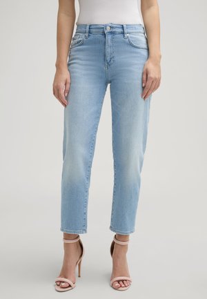 Hellblaue Denim-Jeans mit hohem Bund, geradem Beinsaum, leichtem Verblassen und Fünf-Taschen-Styling, kombiniert mit hautfarbenen High-Heels.