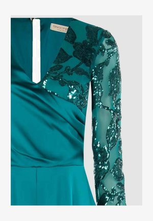 Abito da sera turchese con scollo a V profondo, corpo in raso e maniche lunghe trasparenti con ricamo floreale di paillettes. Lo scollo presenta un'apertura verticale.
