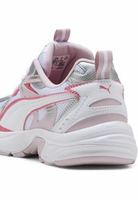 Zapatilla atlética blanca y rosa con superposiciones de malla y sintético, acentos plateados, cuello acolchado y suela texturizada. Cuenta con una lengüeta en el talón.