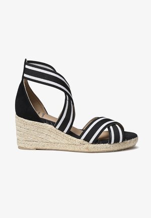 Espadrilles compensées rayées noir et blanc avec une plateforme en jute, dotées de brides en tissu croisées et d'une semelle intérieure douce.