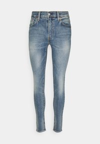 Vaqueros ajustados en denim azul claro, con un diseño de cinco bolsillos, pasadores para cinturón y un cierre de botón. Textura desgastada con acentos de costura.