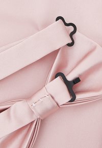 Pale rosa sateng med en bue detalj, med svarte maskinvareklips. Glatt tekstur og forsiktig samlet design.