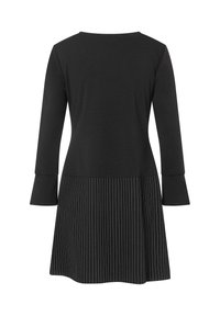 Schwarzes Kleid mit langen Ärmeln und ausgestelltem Schnitt. Das Oberteil besteht aus glattem Stoff, während der Rock vertikale Nadelstreifen aufweist.