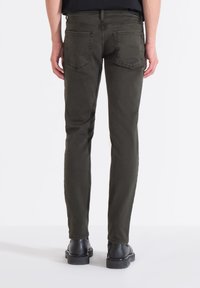 Jeans ajustados de color verde oliva, fabricados en una suave mezcla de algodón, que cuentan con bolsillos traseros y un clásico diseño de cinco bolsillos. Acabados con costuras resistentes.