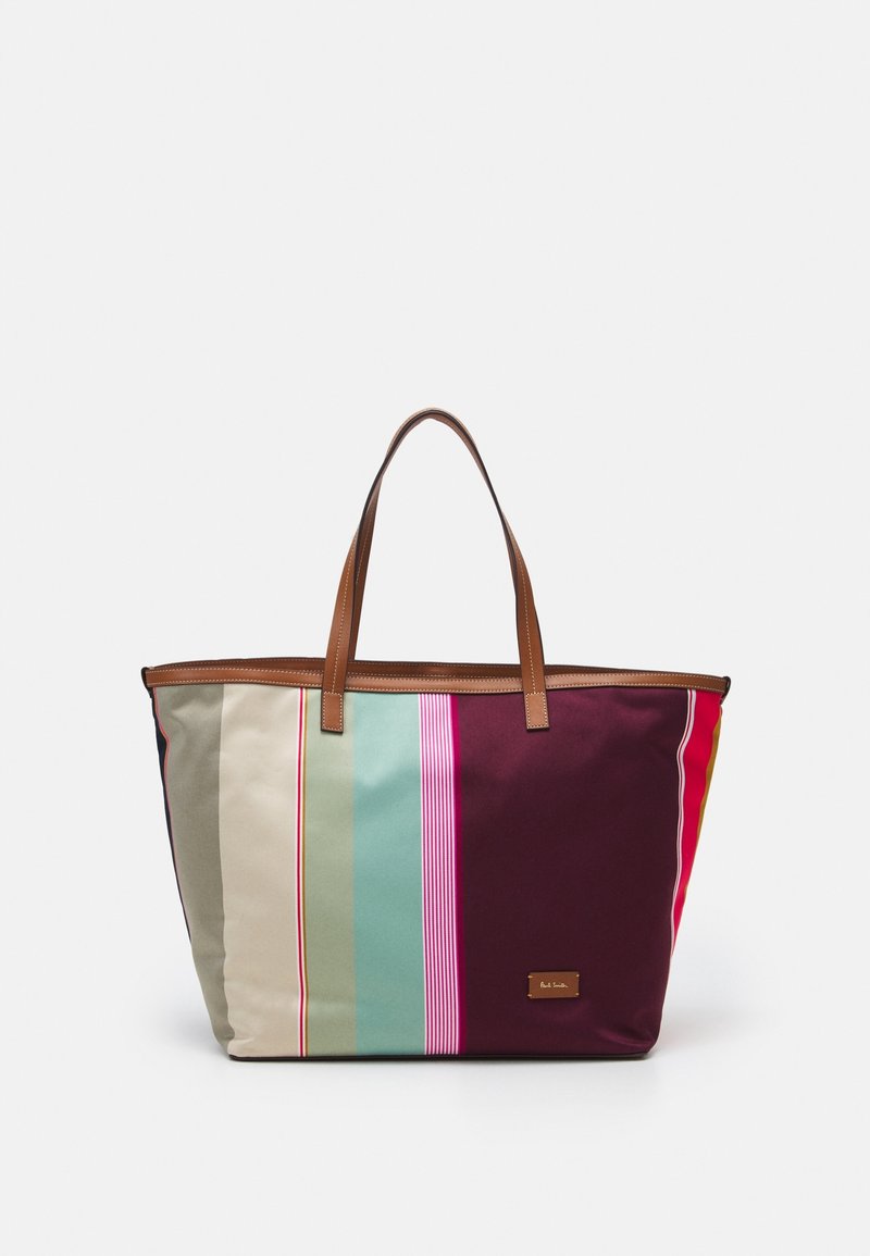 Large tote bag in various colored stripes including beige, teal, and maroon. Features brown leather handles and a metal logo plate.