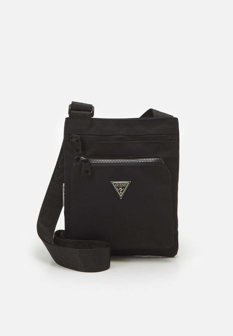 Sac en nylon noir à bandoulière, avec une poche zippée à l'avant, un logo et une sangle ajustable. Texture lisse et design minimaliste.