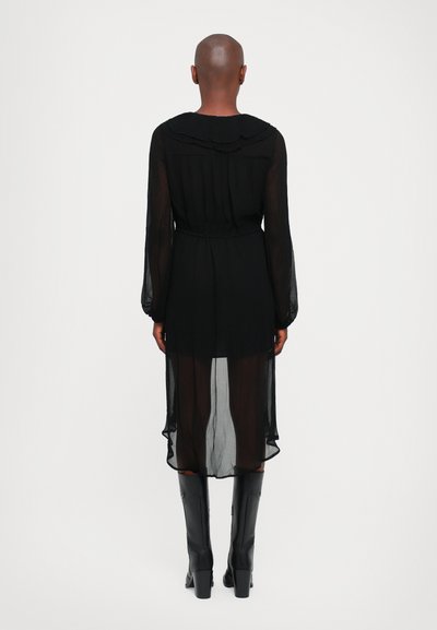 Rochie lungă semi-transparentă neagră, cu guler ondulat, talie strânsă și hem fluid, asortată cu cizme negre din piele înalte.