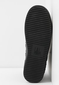Semelle de chaussure de sport noire avec rainures horizontales et logo "billi bi SPORT" embossé au centre sur un fond blanc.