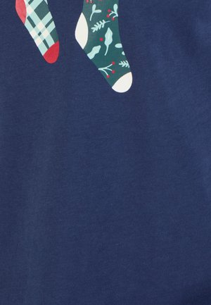 Marineblauwe stof met twee decoratieve sokken. Eén sok is geruit met rode accenten; de andere heeft een groen kerstpatroon met rode bessen.