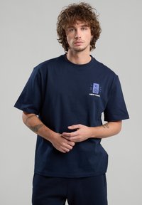 Navy blue cotton t-shirt with short sleeves, featuring a small graphic of a speaker and the text "NEW YORK" in white and blue.