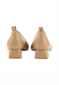 Zapatos de tacón bloque en color beige con parte superior sintética suave, puntera afilada y tirador trasero. Diseño minimalista con acabado mate.