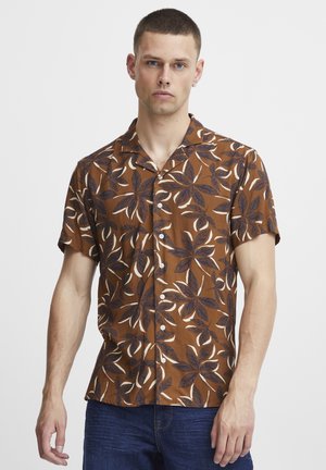 Camisa de manga corta marrón con un patrón floral en azul oscuro y blanco, con un diseño de cuello y cierre de botones.